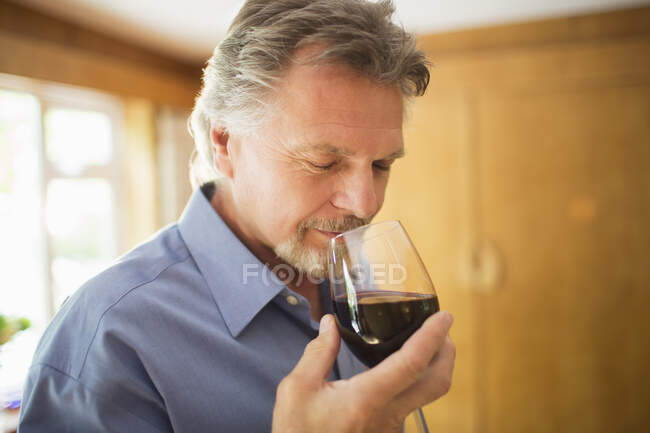 Закройте безмятежного человека, нюхающего и пробующего красное вино — стоковое фото