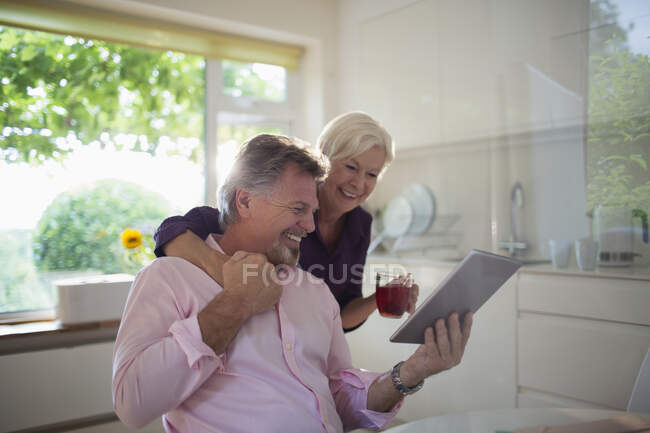 Heureux couple de personnes âgées utilisant une tablette numérique dans la cuisine — Photo de stock