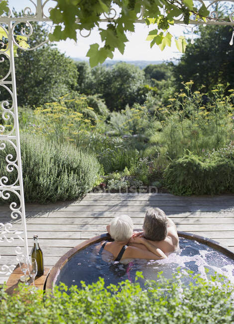 Couple insouciant se détendre dans un bain à remous sur terrasse ensoleillée d'été — Photo de stock
