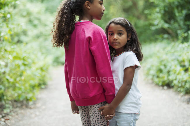 Portrait affectionate sisters holding hands on park path — Stock Photo