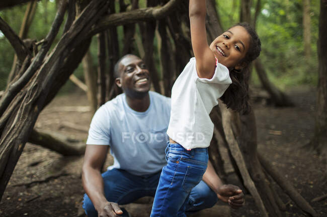 Portrait happy father and daughter playing at tree in woods — Stock Photo