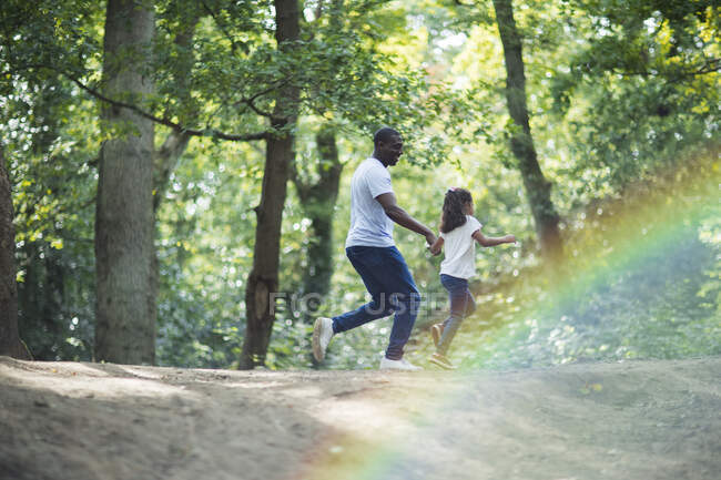 Happy father and daughter running on trail in summer woods — Stock Photo