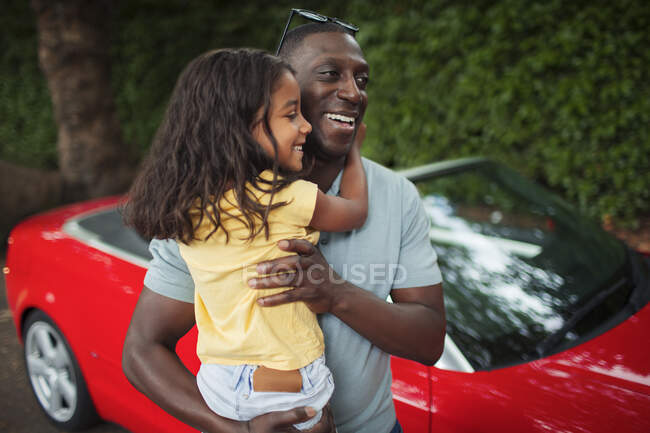 Happy father holding daughter outside convertible — Stock Photo