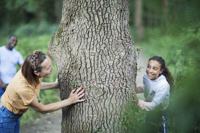 Playful mother and daughter at tree in woods — Stock Photo