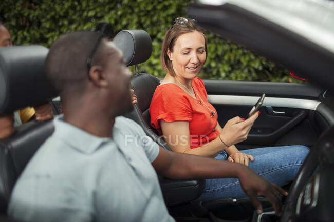 Couple utilisant un téléphone intelligent en décapotable — Photo de stock