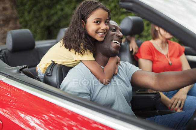 Portrait happy daughter hugging father driving convertible — Stock Photo