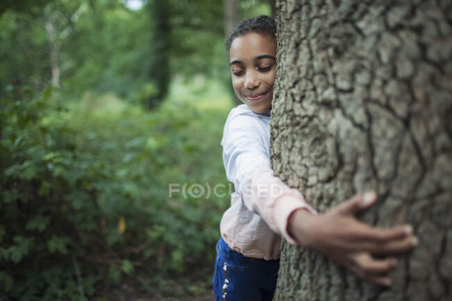 Nettes Mädchen umarmt Baumstamm im Wald — Stockfoto