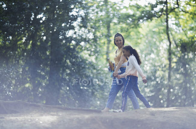 Madre e hija cogidas de la mano senderismo en bosques de verano - foto de stock
