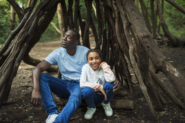 Feliz pai e filha relaxante dentro árvore ramo teepee no bosque — Fotografia de Stock