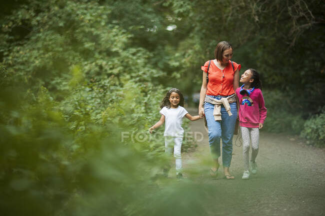 Madre e hijas caminando por el camino en el bosque - foto de stock