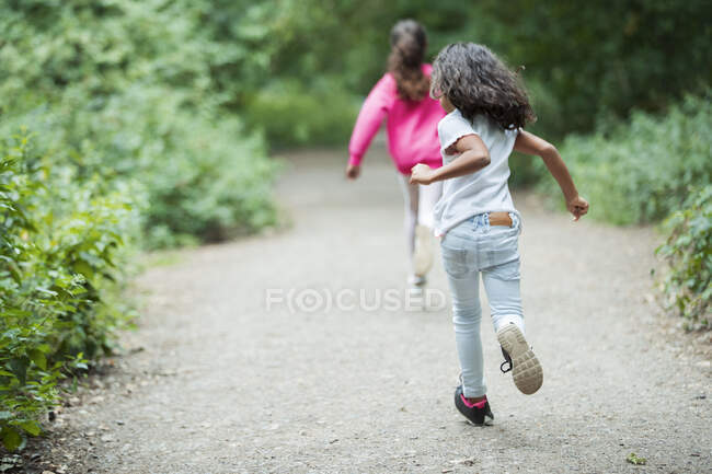 Hermanas despreocupadas corriendo por el sendero del parque - foto de stock