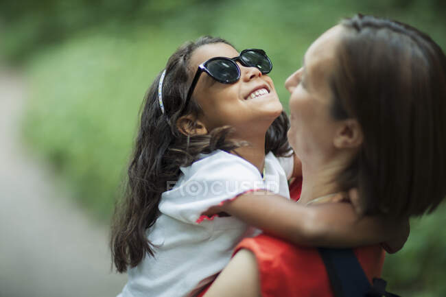 Feliz madre sosteniendo hija en gafas de sol - foto de stock