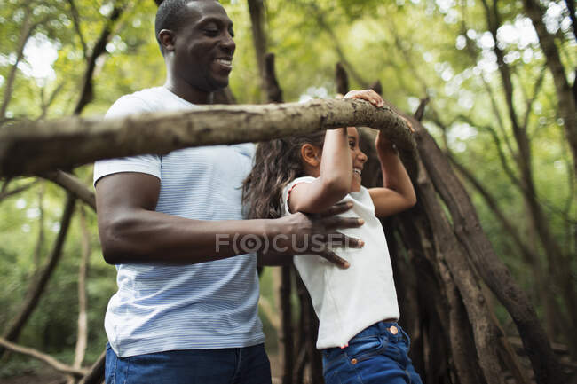 Батько і дочка грають з гілкою в лісі — стокове фото