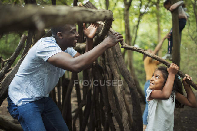 Father and daughter building teepee with branches in woods — Stock Photo