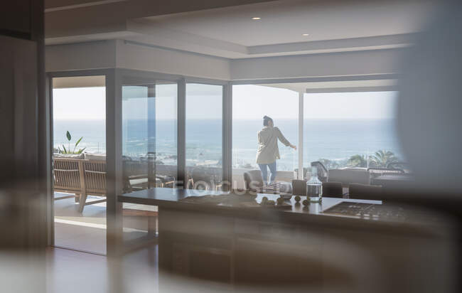 Femme regardant vue sur l'océan ensoleillé sur le balcon de vitrine de maison de luxe — Photo de stock