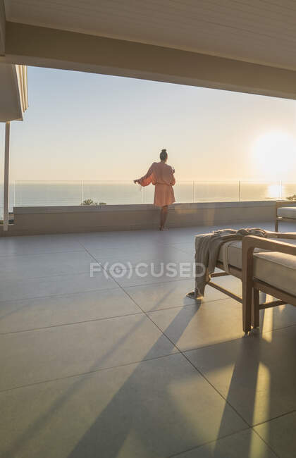 Frau im Bademantel genießt Blick auf den Sonnenuntergang vom Luxus-Balkon — Stockfoto