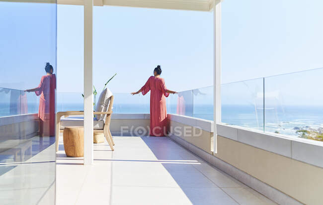 Woman in dress enjoying sunny scenic ocean view from luxury balcony — Fotografia de Stock