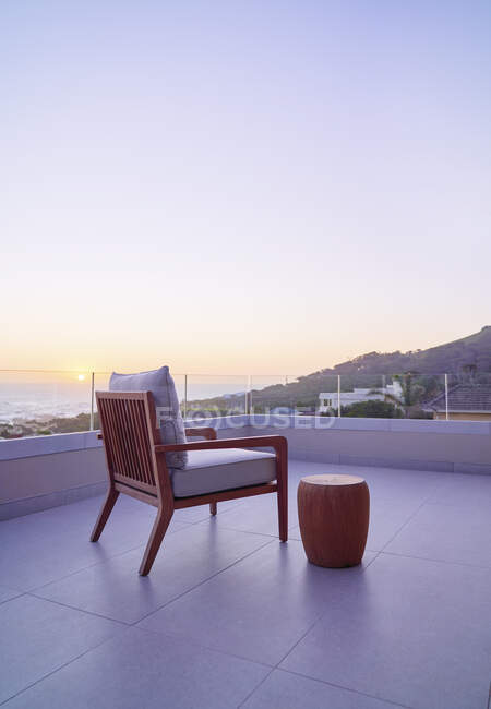 Armchair on luxury balcony with scenic ocean sunset view — Fotografia de Stock
