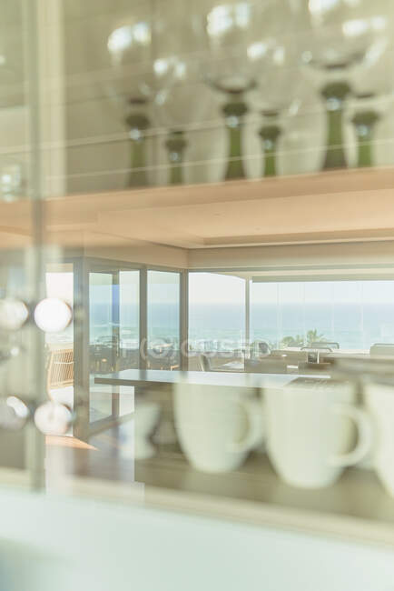 Reflection of sunny ocean view in kitchen cabinet with glassware — Foto stock