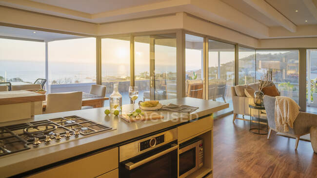 Sonniger Luxus zu Hause Vitrine Innenraum Küche mit Sonnenuntergang Meerblick — Stockfoto