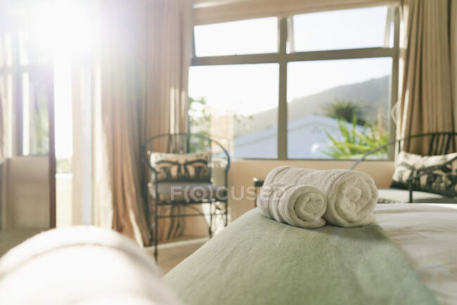 Towels wrapped in rolls on sunny tranquil bed — Foto stock