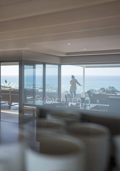 Femme bénéficiant d'une vue panoramique ensoleillée sur l'océan sur le balcon de luxe — Photo de stock