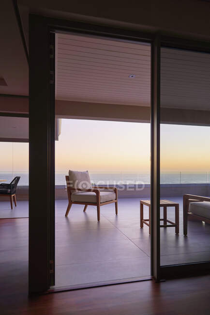 Fauteuil sur la maison de luxe vitrine balcon avec coucher de soleil vue sur l'océan — Photo de stock