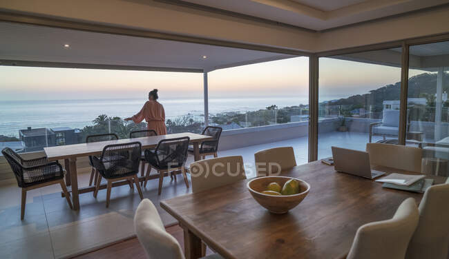 Femme bénéficiant d'une vue panoramique sur l'océan coucher de soleil sur le patio de luxe — Photo de stock