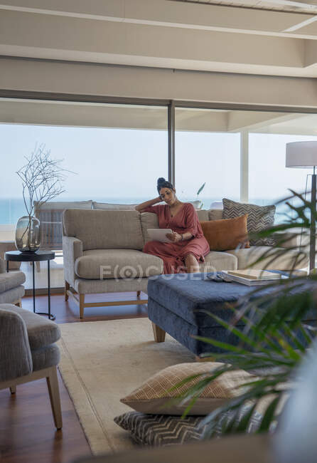 Жінка розслабляється з цифровим планшетом на дивані в розкішній вітальні — стокове фото