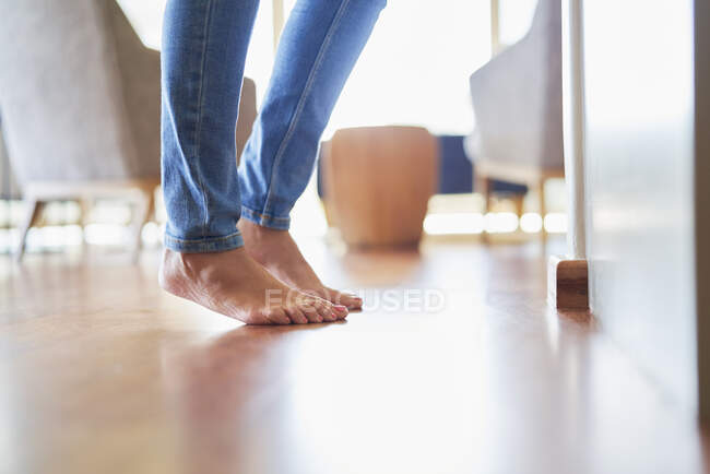 Cerca de los pies desnudos de la mujer en el suelo de madera - foto de stock