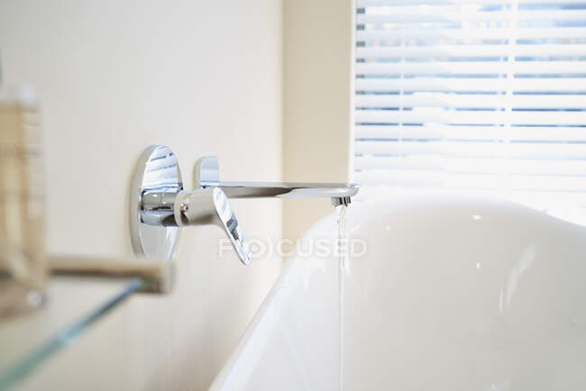 Feche a água da torneira enchendo a banheira de imersão branca no banheiro — Fotografia de Stock