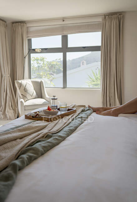 Frühstückstablett auf dem Bett im sonnigen Schlafzimmer am Morgen — Stockfoto
