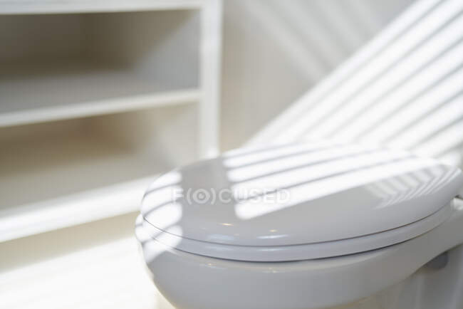Sonnenlicht Schatten über weißem Toilettensitz im Badezimmer — Stockfoto