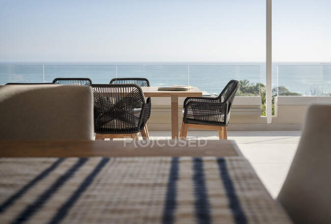 Vista mar atrás da mesa de jantar e cadeiras no pátio de luxo ensolarado — Fotografia de Stock