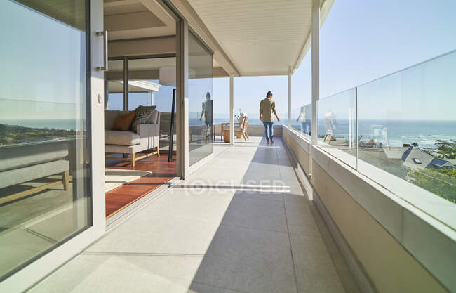 Woman on sunny long luxury balcony with ocean view — Stock Photo