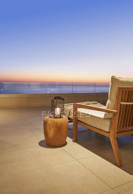 Ліхтар і боковий стіл на розкішному дворику з видом на океан заходу сонця — стокове фото