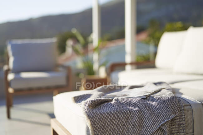 Coperta e rivista sul divano soleggiato patio — Foto stock