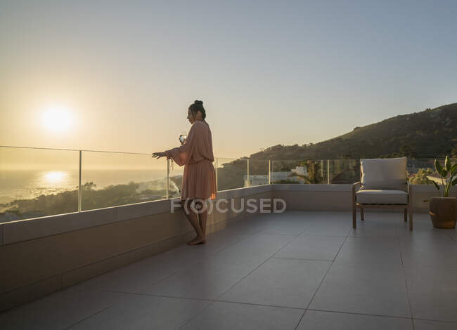 Donna godendo vista panoramica sull'oceano tramonto sul patio di lusso — Foto stock
