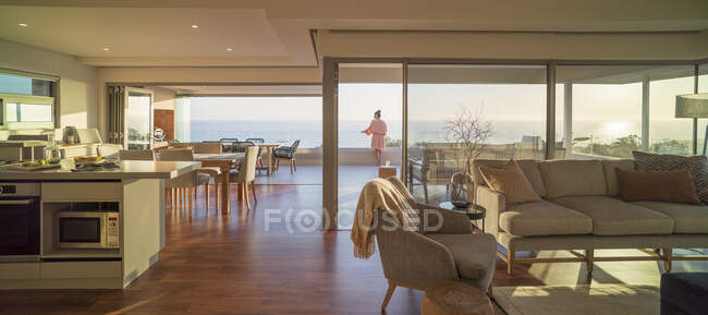 Женщина наслаждается живописным солнечным видом на океан на роскошном балконе — стоковое фото