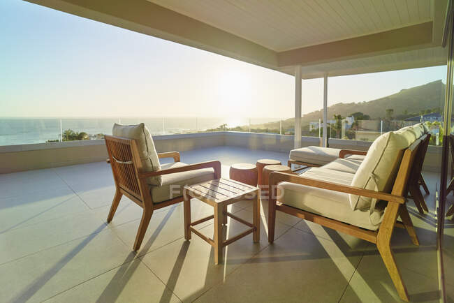 Divano e poltrona su soleggiato patio di lusso tranquillo con vista sull'oceano — Foto stock