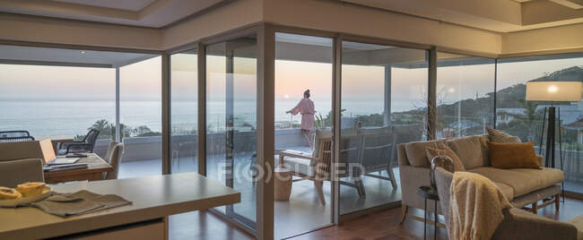 Donna godendo vista panoramica sull'oceano tramonto sul balcone di lusso — Foto stock