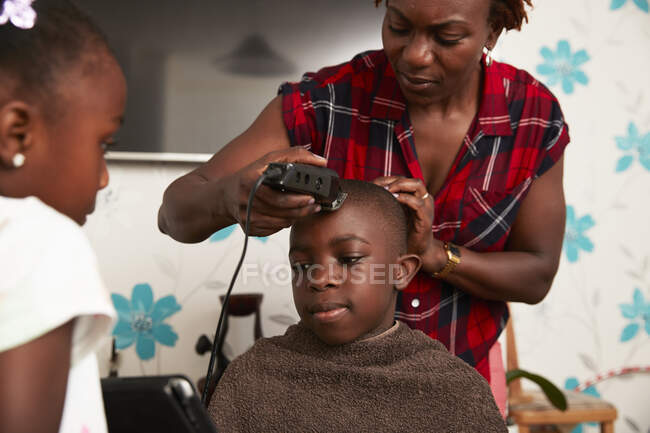 Mãe com aparadores de corte filho cabelo no banheiro — Fotografia de Stock