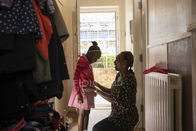Madre aiutare figlia con giacca alla porta d'ingresso — Foto stock