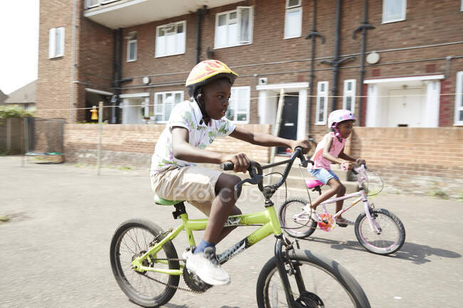 Брат и сестра катаются на велосипедах в солнечном районе — стоковое фото