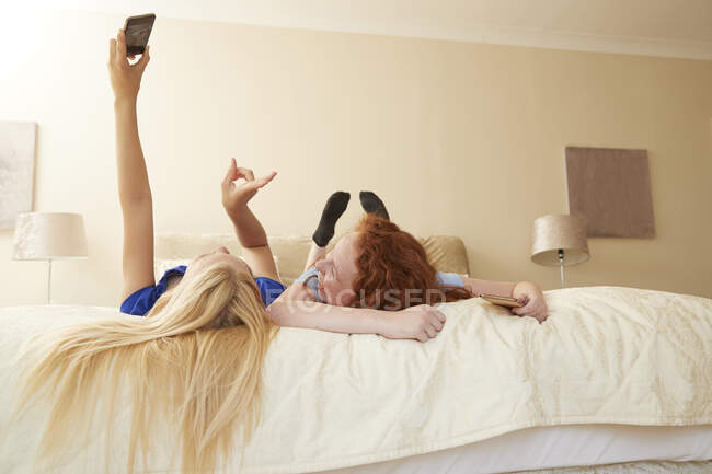 Carefree preteen girl friends taking selfie on bed — Stock Photo