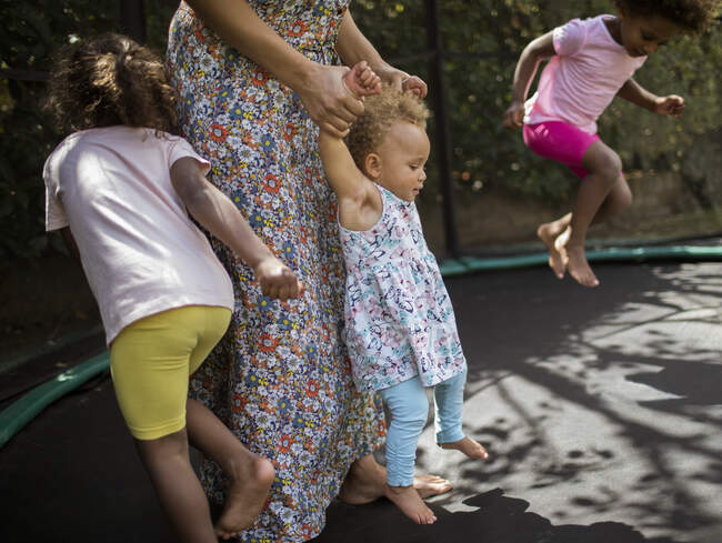 Mother and daughters playing on trampoline — Stock Photo