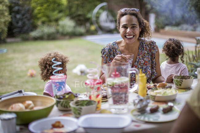 Портрет счастливая мать наслаждается летним барбекю с семьей на патио — стоковое фото