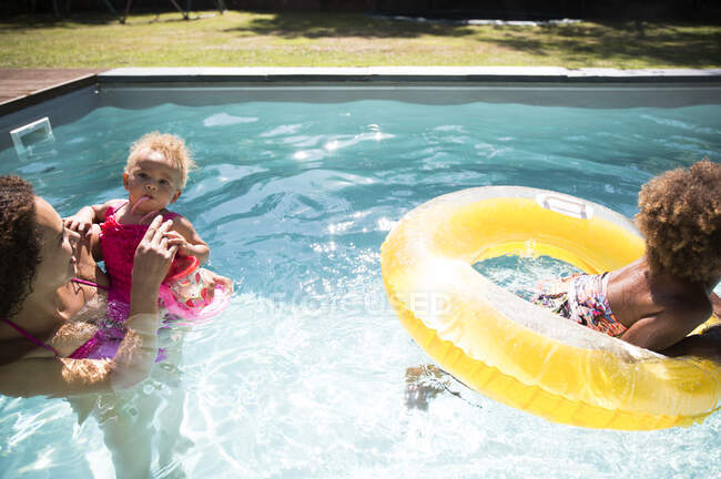 Madre e figlie che giocano nella soleggiata piscina estiva — Foto stock