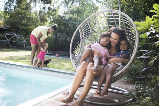 Mãe feliz e filhas abraçando na cadeira de balanço de pátio de verão — Fotografia de Stock