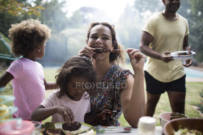 Madre e hija disfrutando de almuerzo barbacoa en el patio - foto de stock
